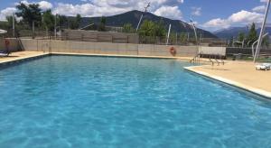 una gran piscina de agua azul con sillas. en Apartamento en Las Margas, en Sabiñánigo