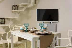 uma mesa de jantar branca com cadeiras e uma televisão em La Rosa del Corso em Fasano