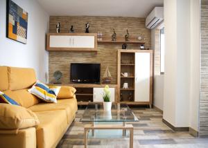 ein Wohnzimmer mit einem Sofa und einem TV in der Unterkunft Sur Suites Palmeras 3 in Fuengirola