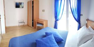 a bedroom with a blue bed with blue curtains and a desk at Hotel Mare Blu -- boutique in Pineto