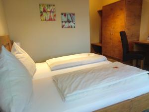 two twin beds in a room with a chair at Hotel Daimerwirt in Moosinning