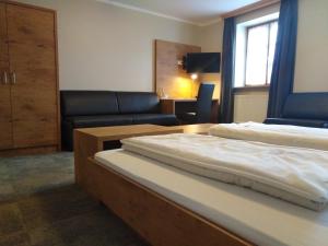 a hotel room with a bed and a couch at Hotel Daimerwirt in Moosinning