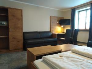 a hotel room with a couch and a table at Hotel Daimerwirt in Moosinning