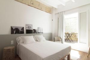 a white bedroom with a bed and a window at Mon hotel in Ciutadella