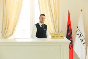 un hombre con traje y corbata de pie en un podio en Royal Hill Hotel, en Tirana