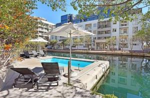 a swimming pool with chairs and an umbrella next to a building at Waterfront Stays in Cape Town