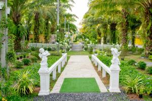 a walkway in a garden with white fences and plants at View Dao Jantra in Chachoengsao