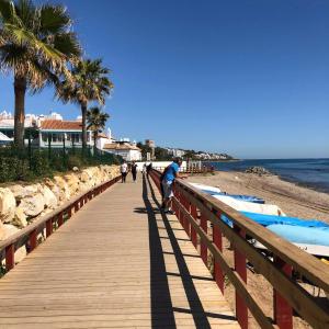 een man die over een houten promenade loopt op het strand bij Calahonda apartamento a 150 metros de la playa Nueva Gerencia in Sitio de Calahonda