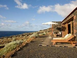 a house with an umbrella and a chair and a table and an umbrella at casa La Perdiz in Valverde