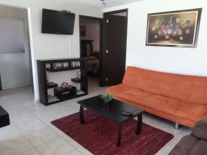 a living room with an orange couch and a table at Departamento cómodo y completo en Toluca in Toluca