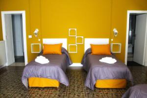 two beds in a room with a yellow wall at B&B Kike in Catania