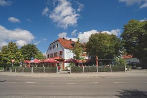 a building with red umbrellas on the side of a street at Hotel Daimerwirt in Moosinning