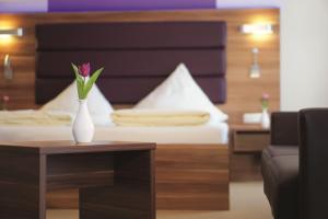 a vase with a flower on a table next to a bed at Hotel Daimerwirt in Moosinning
