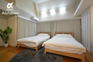 2 aparte bedden in een slaapkamer met witte lakens bij Alphabed TakamatsuKawaramachi WEST 701 / Vacation STAY 21586 in Takamatsu