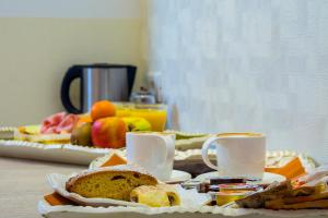 einen Tisch mit zwei Tassen und einem Teller Brot und Obst in der Unterkunft Zefiro Home in Rom