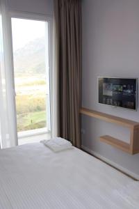 a bedroom with a bed and a large window at Hotel Auto Grill Roberti in Tepelenë