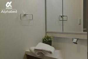 baño con espejo y lavabo con toallas en Alphabed TakamatsuFurujinmachi 902 / Vacation STAY 21916 en Takamatsu