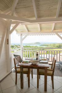 a dining room with a table and chairs on a balcony at Bungalow Vanille Pacane - Vue Mer avec Spa Privé in Les Trois-Îlets