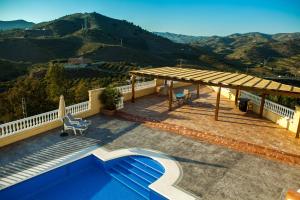 a house with a deck with a view of the mountains at Villa El Palomar Azul with pool and sea view in Benajarafe