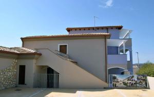 a white house with a staircase in front of it at Appartamenti MareBlu in Badesi