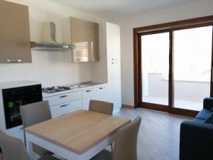 a kitchen with a wooden table and a table and chairs at Appartamenti MareBlu in Badesi