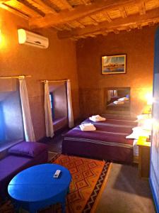 a room with two beds and a couch and a table at Dar Mouna La Source in Aït Benhaddou