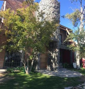 a brick house with a tree in front of it at Apart Hotel Abedules in Puerto Madryn