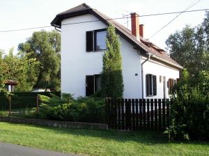 a white house with black windows and a fence at Mária Villa in Balatonmáriafürdő