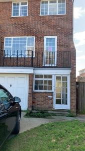 a brick house with white doors and a balcony at QUEEN GUEST HOUSE in Gillingham