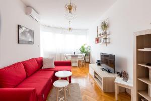 a living room with a red couch and a tv at "Apartment Zagreb Idila Center", with a balcony, speed WiFi in Zagreb