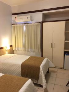 a hotel room with two beds and a closet at Portal da Princesa Hotel in Feira de Santana