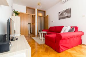 a living room with a red couch and a tv at "Apartment Zagreb Idila Center", with a balcony, speed WiFi in Zagreb
