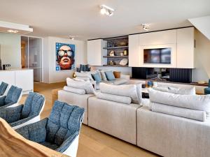 uma sala de estar com um grande sofá e cadeiras em Luxe apmt Zwembad Sauna op Duin aan Strand, registratie 17146E3088BEB97A4E16 em Cadzand-Bad