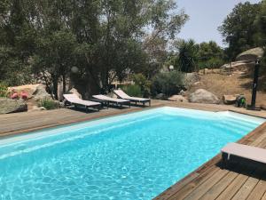 a swimming pool with chairs and a wooden deck at Villa Filippi in Porto-Vecchio
