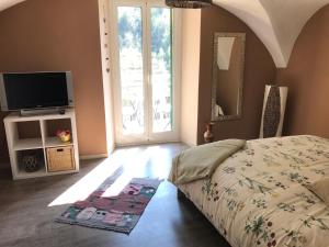 a bedroom with a bed and a tv and a window at La Paramira in Pigna