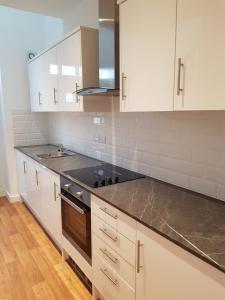 a kitchen with white cabinets and a black stove at Charlie Mews in Farnborough