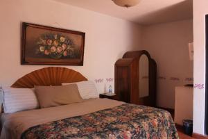 Comonfort的住宿－Hotel Posada Chamacuero，卧室配有一张床,墙上挂有绘画作品