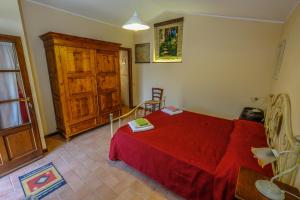 um quarto com uma cama vermelha e um armário de madeira em Agriturismo Il Torrione em Certaldo