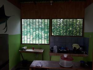 a kitchen with two windows and a sink and a table at Hotel Jhazmin Aeropuerto in Drake