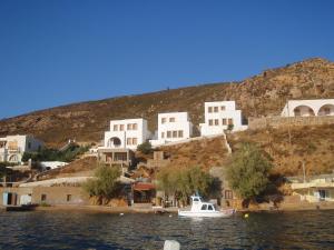 a white boat in the water in front of houses at Patmos Houses in Patmos