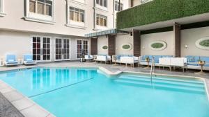 洛杉磯的住宿－Mosaic Hotel Beverly Hills，一座带蓝色椅子的游泳池和一座建筑