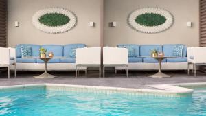 a pool with blue couches and chairs next to a swimming pool at Mosaic Hotel Beverly Hills in Los Angeles