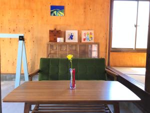 a table and a vase with a flower on it at 青とサイダー in Oshima