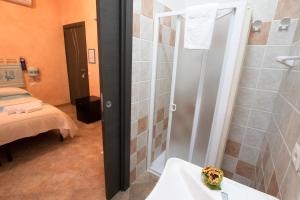 uma casa de banho com um chuveiro, um lavatório e uma cama em B&B Sa Lumenaria "da Raimonda" em Sorgono