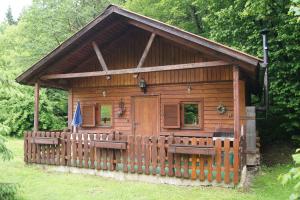 eine Holzhütte mit einem Zaun im Gras in der Unterkunft Ferienhütten Brandtner in Rossleithen