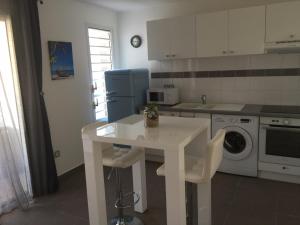 a kitchen with a white table and white appliances at Beau studio proche de la mer in Le Moule