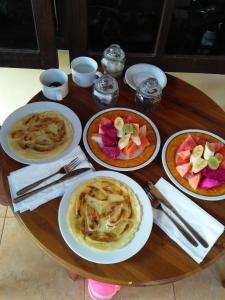 una mesa de madera con platos de comida. en Wirya House, en Ubud