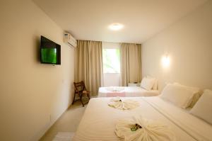 een hotelkamer met twee bedden en een televisie bij Vila do Morro Pousada in Morro de São Paulo