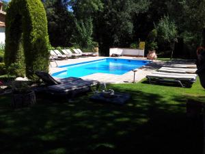 a swimming pool with chaises and chairs in a yard at Hotel Rural Convento Santa Maria de la Sierra in Arroyo Frio