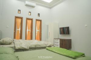 a bedroom with two beds and a tv in it at M Stay Guest House Jogja in Yogyakarta
